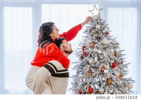 couple having fun decorating christmas tree 108611628