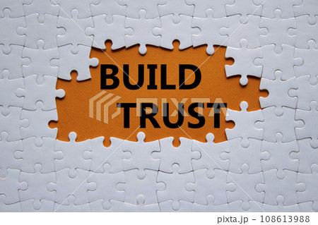 Build trust symbol. White puzzle with words Build trust. Beautiful orange background. Business and Build trust concept. Copy space. Build trust symbol. White puzzle with words Build trust. Beautiful orange background. Business and Build trust concept. Copy space. 108613988