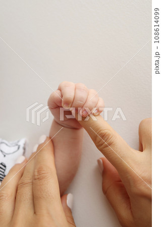 Parents' hands hold the fingers of a newborn baby. The hand of a mother and father close-up holds the fist of a newborn baby. Family health and medical care. Professional photo on white background Parents' hands hold the fingers of a newborn baby. The hand of a mother and father close-up holds the fist of a newborn baby. Family health and medical care. Professional photo on white background 108614099
