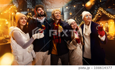 Group portrait of happy cheerful people, friends with cup of hot warming mulled-wine and enjoying moment before New Year Day. 108614377