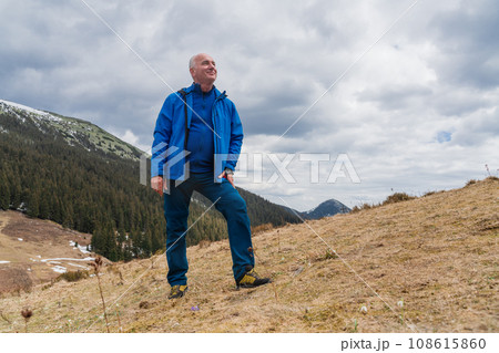Man hiker enjoys snowdrops blooming at Carpathian mountains Man hiker enjoys snowdrops blooming at Carpathian mountains 108615860