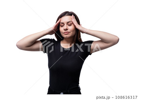 25 year old brunette woman concentrates and has closed her eyes and holds her head in her hands 108616317