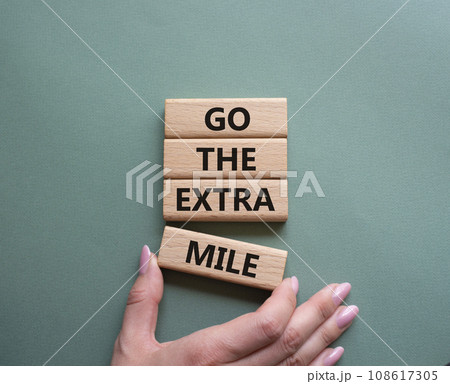 Go the extra mile symbol. Wooden blocks with words Go the extra mile. Businessman hand. Beautiful grey green background. Business and Go the extra mile concept. Copy space. Go the extra mile symbol. Wooden blocks with words Go the extra mile. Businessman hand. Beautiful grey green background. Business and Go the extra mile concept. Copy space. 108617305