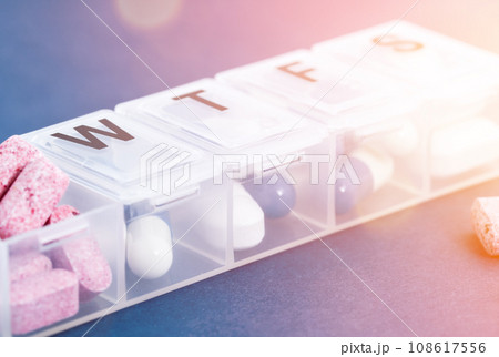 Capsule in the pill box on the blue background. Pill dispenser. Capsule in the pill box on the blue background. Pill dispenser. 108617556