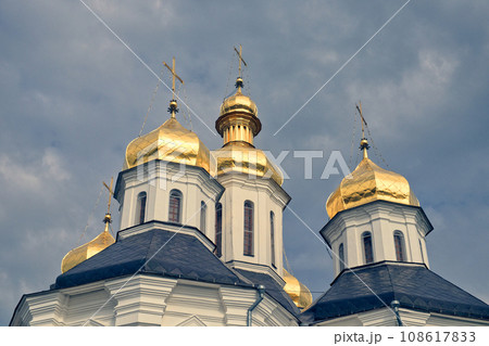 The golden domes of a Orthodox Church, standing majestically against a backdrop of a clear blue sky. Gilded domes of an ancient Orthodox church against the sky. 108617833
