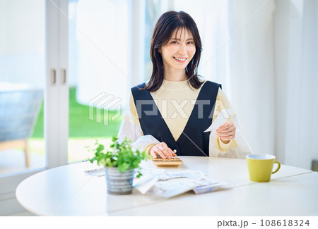 レシートを見ながら電卓で計算する主婦 108618324