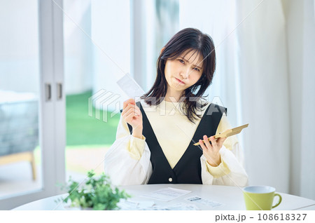 レシートを見ながら電卓で計算する主婦 108618327