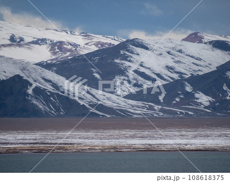 Dramatic landscape with snowy mountaintop in low cloudy sky. White snow on black rocks in low clouds. Awesome view to snow mountain peak in clouds. Lake with mountain, landscapes of Mongolia. Dramatic landscape with snowy mountaintop in low cloudy sky. White snow on black rocks in low clouds. Awesome view to snow mountain peak in clouds. Lake with mountain, landscapes of Mongolia. 108618375