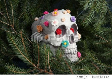 skull covered with multiple plastic flowers in different colors 108618442