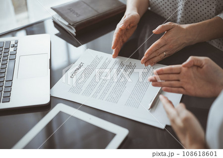 Business people discussing contract signing deal while sitting at the glass table in office, closeup. Partners or lawyers working together at meeting. Teamwork, partnership, success concept Business people discussing contract signing deal while sitting at the glass table in office, closeup. Partners or lawyers working together at meeting. Teamwork, partnership, success concept 108618601