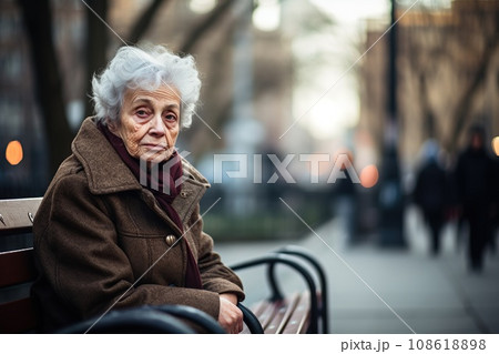 Elderly woman sitting on a bench in park, loneliness Elderly woman sitting on a bench in park, loneliness 108618898