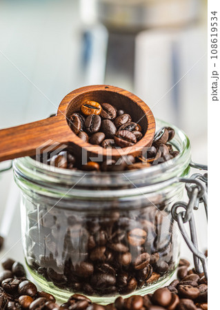 Roasted coffee beans in wooden scoop  on white kitchen table. 108619534