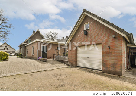 a brick house with two garages in the front and one on the other side that has a white door 108620371