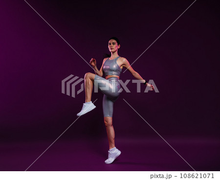Full length of young slim female in silver sportswear warming up on magenta backdrop Full length of young slim female in silver sportswear warming up on magenta backdrop 108621071