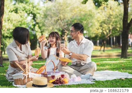 Happy Asian family enjoying picnic outing in the summer outdoors at the park. Happy Asian family enjoying picnic outing in the summer outdoors at the park. 108622179