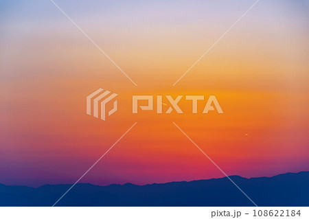 日暮れの西の空の夕焼け 山並みのシルエットと遠い飛行機雲　a-1 108622184