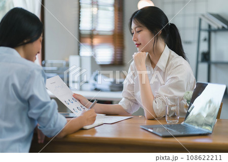 Two happy asian colleagues discussing new project, businesswomen using digital laptop together in office. Two happy asian colleagues discussing new project, businesswomen using digital laptop together in office. 108622211