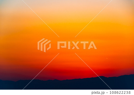 日暮れの西の空の夕焼け 山並みのシルエットと遠い飛行機雲 暖色 a-2 高彩度コントラスト 日暮れの西の空の夕焼け 山並みのシルエットと遠い飛行機雲 暖色 a-2 高彩度コントラスト 108622238