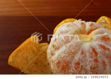 木のテーブルの上に置かれた皮をむいたミカン 108624053