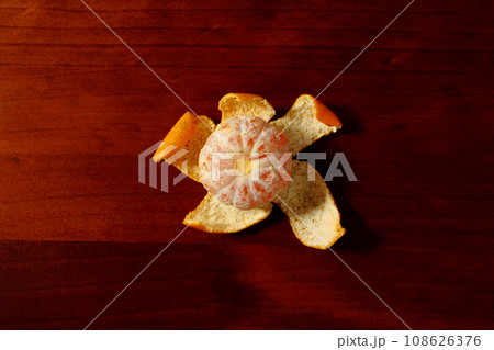 木のテーブルの上に置かれた皮をむいたミカン 108626376