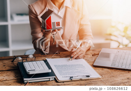 Real estate broker agent presenting and consult to customer to decision making sign insurance form agreement, buy and sell home model, concerning mortgage loan offer for and house insurance Real estate broker agent presenting and consult to customer to decision making sign insurance form agreement, buy and sell home model, concerning mortgage loan offer for and house insurance 108626612