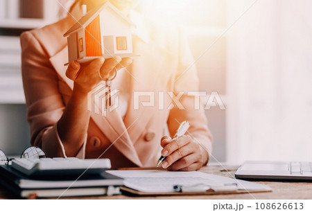 Real estate broker agent presenting and consult to customer to decision making sign insurance form agreement, buy and sell home model, concerning mortgage loan offer for and house insurance 108626613