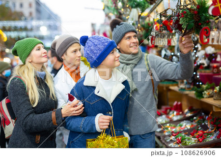 Friendly family chooses Christmas souvenirs and toys Friendly family chooses Christmas souvenirs and toys 108626906