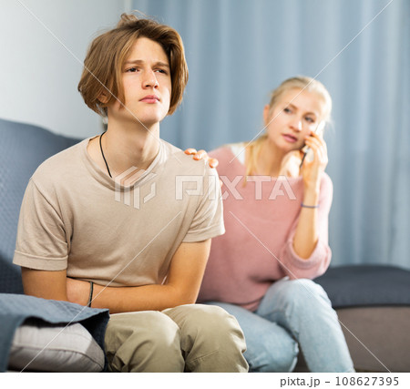 Woman sitting near her sad son and calling to doctor 108627395