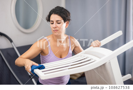 Woman wipes chair with rag, tidying up apartment 108627538