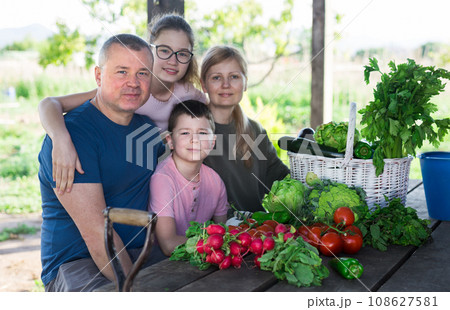 Family posing in garden with picked vegetables 108627581