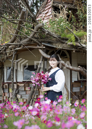 小さな小屋の前　コスモスの庭　花束を持つ女性 108630053