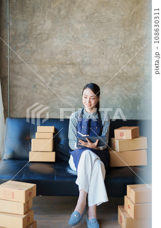 Starting small business entrepreneur of independent Asian female online seller talking on the phone with a customer and packing products for delivery to the customer. and SME delivery concept. 108630311