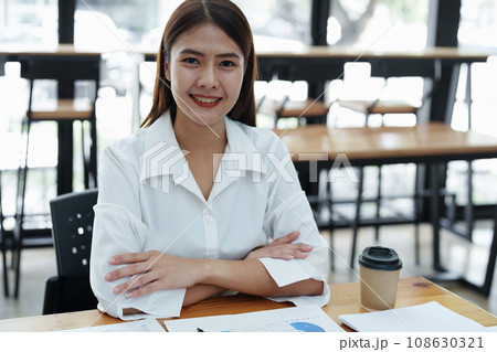 Portrait of a female business owner showing a happy smiling face as he has successfully invested his business using computers and financial budget documents at work. 108630321