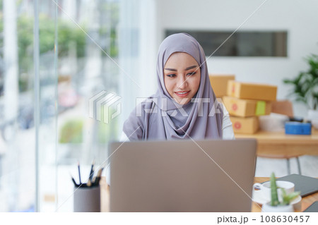 Beautiful Muslim woman using computer to check customer orders, small business owners or sme concepts. 108630457