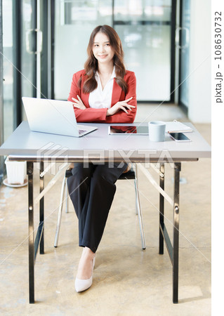 Portrait of a woman business owner showing a happy smiling face as he has successfully invested her business using computers and financial budget documents at work. Portrait of a woman business owner showing a happy smiling face as he has successfully invested her business using computers and financial budget documents at work. 108630732
