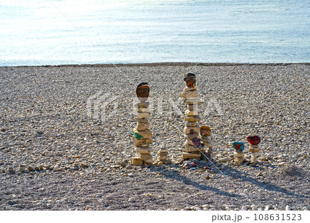 figures made of stones on the beach against the backdrop of the sea. A vertical figure made of stones stands against the backdrop of water. Inscriptions of gratitude on stones 108631523