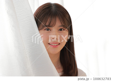 カーテンから顔を覗かせる若い女性_クローズアップ2 108632783