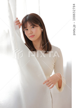 カーテンから顔を覗かせる若い女性_1 カーテンから顔を覗かせる若い女性_1 108632784