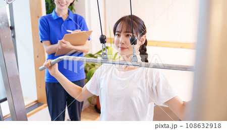 スポーツジムで運動する女性とトレーナー 108632918