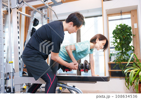 スポーツジムで運動する女性とトレーナー(ダンベル) スポーツジムで運動する女性とトレーナー(ダンベル) 108634536