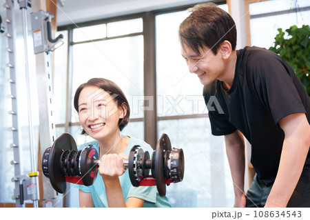 スポーツジムで運動する女性とトレーナー（ダンベル） 108634543