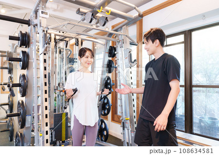 スポーツジムで運動する女性とトレーナー(ケーブルマシン) スポーツジムで運動する女性とトレーナー(ケーブルマシン) 108634581