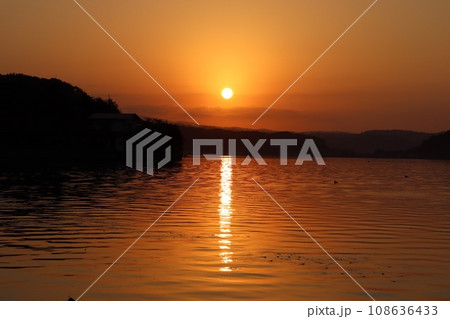 初冬の湖山池に落ちるオレンジ色の夕陽 108636433