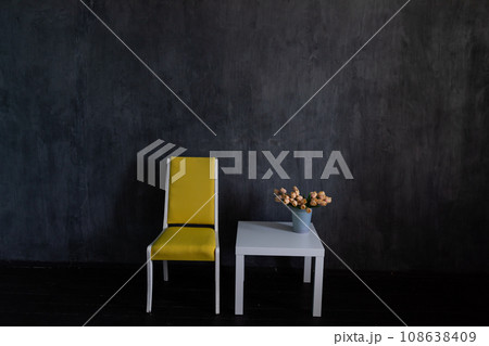 chair and coffee table with flowers in dark room interior 108638409