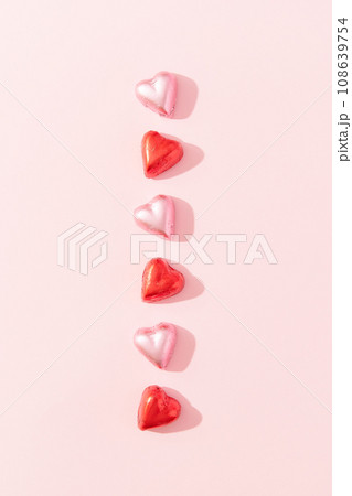 Vertical line made of heart shaped chocolate candies on pink background 108639754