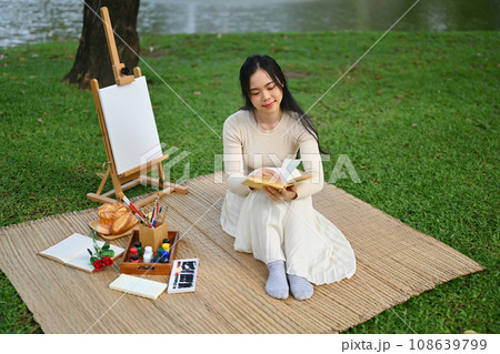 Peaceful young woman reading interesting book and enjoying free time at green park 108639799