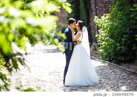 The bride and groom walk together in the park. Pretty bride and stylish groom. Wedding day. Marriage. 108640070