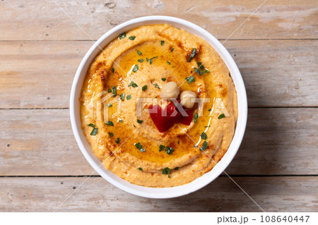 Roasted red pepper hummus in white bowl on wooden table Roasted red pepper hummus in white bowl on wooden table 108640447