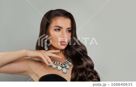 Nice fashion model woman brunette with long shiny curly hair, diamond jewelry earring and necklace Nice fashion model woman brunette with long shiny curly hair, diamond jewelry earring and necklace 108640635
