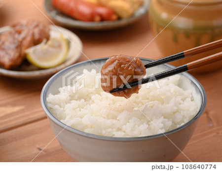 ご飯にのせた梅干しを箸で持ち上げる 108640774